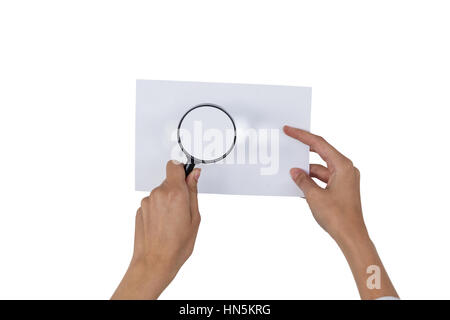 Close-up of woman holding loupe sur papier contre fond blanc Banque D'Images