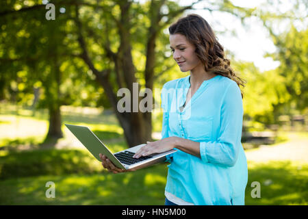 Woman using laptop in park sur une journée ensoleillée Banque D'Images