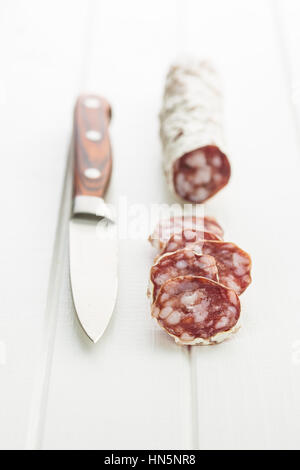 Tranches de salami savoureux sur tableau blanc. Banque D'Images