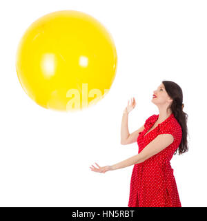 Belle femme en robe rouge de la capture d'un ballon jaune isolé sur fond blanc Banque D'Images