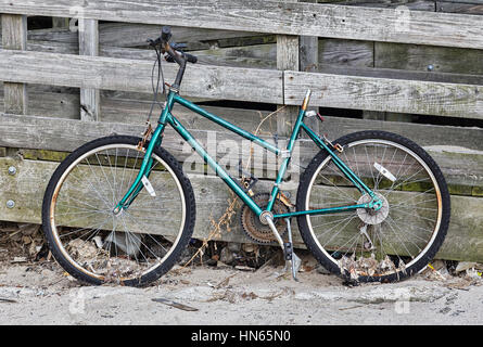 Un vélo abandonné appuyé contre une clôture en bois Banque D'Images