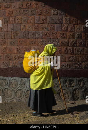 Moine éthiopien femme marche avec un lourd sac sur son dos, région d'Amhara, Lalibela, Éthiopie Banque D'Images