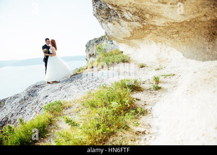 Gorgeous blonde Bride and Groom classy sur les rochers, au milieu de la se Banque D'Images