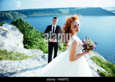 Gorgeous blonde Bride and Groom classy sur les rochers, au milieu de la se Banque D'Images