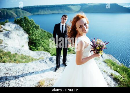 Gorgeous blonde Bride and Groom classy sur les rochers, au milieu de la se Banque D'Images
