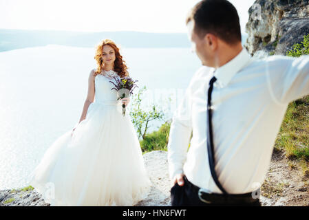 Gorgeous blonde Bride and Groom classy sur les rochers, au milieu de la se Banque D'Images