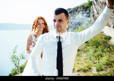 Gorgeous blonde Bride and Groom classy sur les rochers, au milieu de la se Banque D'Images