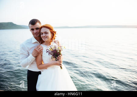 Gorgeous blonde Bride and Groom classy sur les rochers, au milieu de la se Banque D'Images