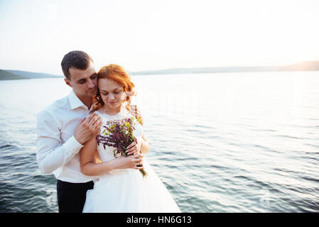 Gorgeous blonde Bride and Groom classy sur les rochers, au milieu de la se Banque D'Images