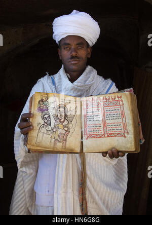 Prêtre de l'église éthiopienne orthodoxe dans l'église Asheten mariam rock taillé avec une vieille Bible, région d'Amhara, Lalibela, Éthiopie Banque D'Images