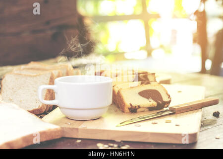 Tranches de gâteau de beurre et de café chaud sur la table de bois mou du soleil. évasé. Banque D'Images