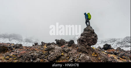 Debout sur le roc, randonneur alpin Tongariro Crossing avec de la neige, Parc National de Tongariro, Southland, Nouvelle-Zélande Banque D'Images