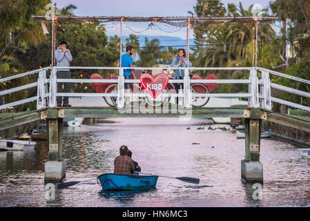 Venise, USA - 25 décembre 2015 : en couple romantique du bateau au pont-canal avec kiss signe et les gens sur des vélos à nuit Banque D'Images