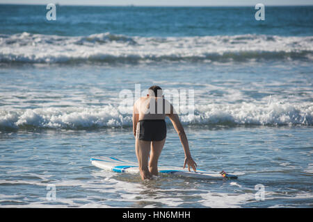 Athletic homme musclé avec trunks maillot de surf directeurs dans les eaux peu profondes de derrière Banque D'Images