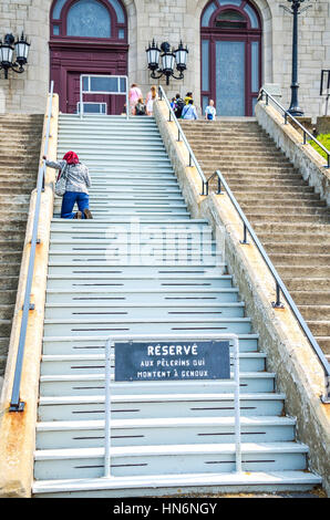 Montréal, Canada - 25 juillet 2014 : personne priant sur les marches de l'Oratoire Saint-Joseph du Mont-Royal avec signe Banque D'Images