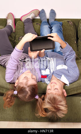 Petite fille et garçon couché à l'envers sur le lit et jouer avec tablet Banque D'Images