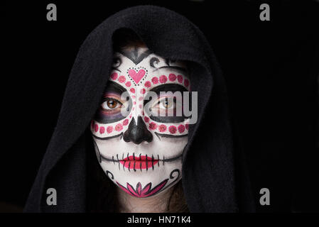 Crâne Halloween maquillage sur visage femme couverte par manteau isolé sur black Banque D'Images