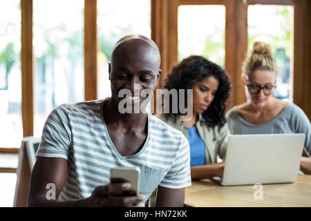 Smiling man using mobile phone in cafÃƒÂ© Banque D'Images