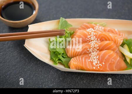 Plaque en forme de bateau sur sushi avec des baguettes et de la sauce Banque D'Images