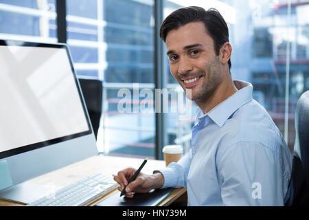 Portrait of male designer graphique à l'aide de tablette graphique at desk in office Banque D'Images