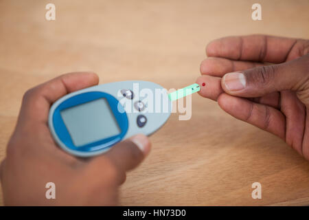 Close-up de l'homme test les mains avec du sucre dans le sang contre diabete fond de bois Banque D'Images