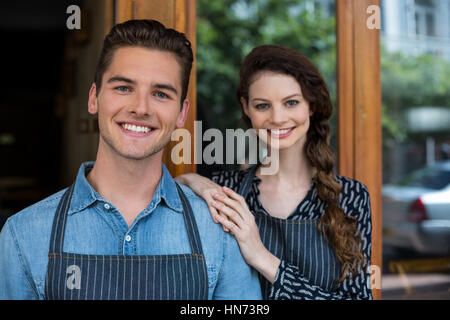 Portrait of smiling waiter et serveuse debout à l'extérieur du cafe Banque D'Images