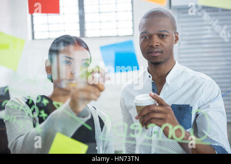 Des collègues de la lecture des notes autocollantes sur verre in office Banque D'Images