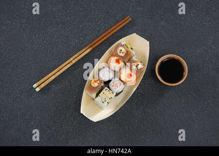 Plaque en forme de bateau sur sushi avec des baguettes et de la sauce Banque D'Images