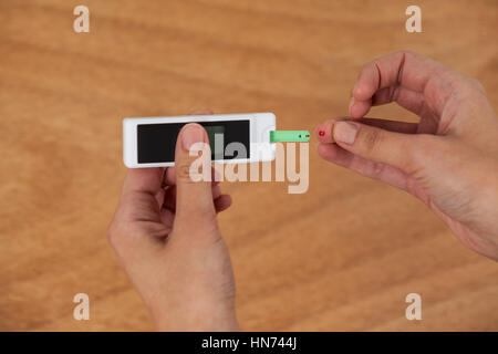 Close-up of woman mains avec du sucre de sang test diabete contre fond de bois Banque D'Images