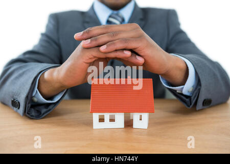 Mid section of businessman protéger house model with hands Banque D'Images