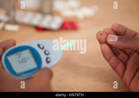 Close-up de l'homme test les mains avec du sucre dans le sang contre diabete fond de bois Banque D'Images