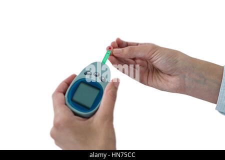 Close-up of mans part tester la glycémie glucomètre avec against white background Banque D'Images