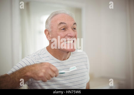 Portrait of senior man holding toothbrush dans la salle de bains à la maison Banque D'Images