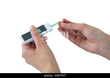 Close-up of woman mains avec du sucre de sang test diabete contre fond blanc Banque D'Images