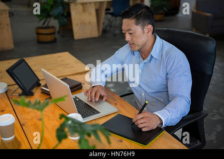 Designer graphique dessin sur une tablette graphique while using laptop in office Banque D'Images