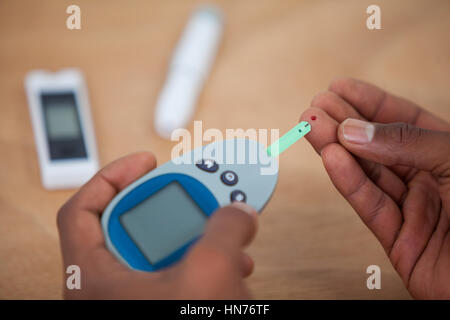 Close-up de l'homme test les mains avec du sucre dans le sang contre diabete fond de bois Banque D'Images