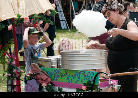 Deux enfants qui la regardent, en prévision d'une femme à faire de la barbe à papa au Port Eliot Cornwall Festival Banque D'Images