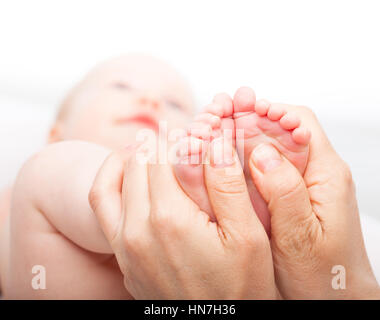 Gros plan sur trois mois baby girl recevoir massage des pieds d'une femme massothérapeute. La caméra est centrée sur les pieds de l'enfant. Visage est flou dans Banque D'Images