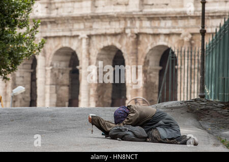 Rome, Italie- femme sans-abri portant sur le terrain la mendicité pour de l'argent en face du célèbre amphithéâtre de pierre connue sous le nom de Colisée romain situé à l'Est Banque D'Images