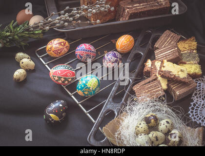 La vie encore Pâques avec éléments de fête traditionnel. Oeufs de cailles, pain, gâteau, pysanka, willow tree brunchs. Stylisme culinaire sombre Banque D'Images