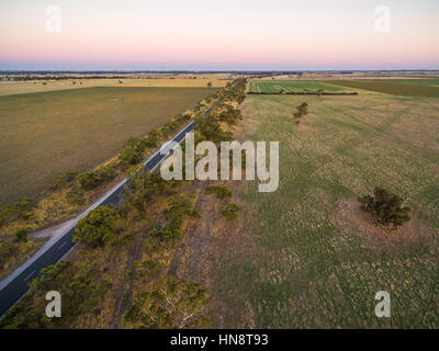 Les pâturages et prairies rurales en Australie au coucher du soleil Vue aérienne avec chemin rural traversant Banque D'Images