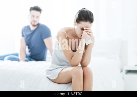 Jeune couple dans la chambre à coucher, la femme est assise seule et pleurer, difficultés relationnelles notion Banque D'Images