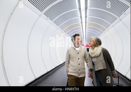 Couple dans le couloir du métro tirant poussette. Banque D'Images