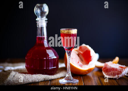 Pamplemousse doux cordial alcoolique dans la carafe avec un verre sur un tableau sombre Banque D'Images