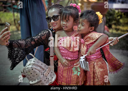 Selfie Asian.Chinese touriste femme utilisant un smartphone et prendre une photo égoïste avec deux jeunes filles dansantes de Thaïlande dans la robe traditionnelle. Banque D'Images