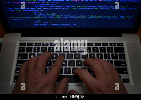 Code Man typing on laptop computer Banque D'Images