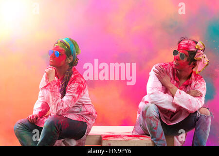 Les jeunes hommes indiens assis sur un banc, couvert de poudre de couleur lors du festival couleur holi Banque D'Images