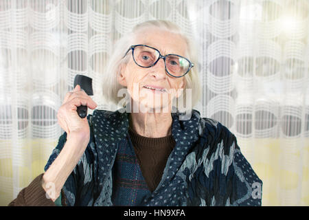 Senior woman holding un peigne à la maison Banque D'Images