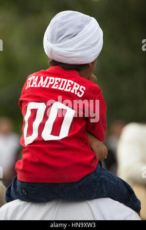 Jeune garçon habillé en rouge et blanc chemise Stampeders turban pour célébration de la fête du Canada dans la région de Eau Claire, centre-ville de Calgary Banque D'Images