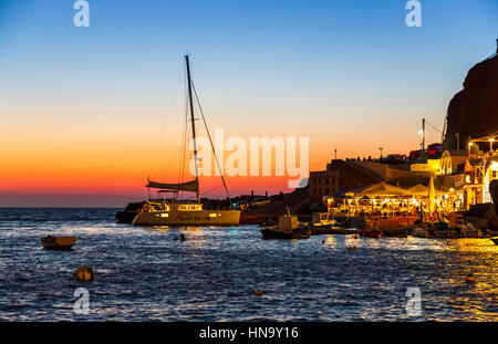 Baie Ammoudi restaurants de poissons et des bateaux dans la nuit dans la lumière résiduelle après le coucher du soleil, Oia, Santorin, une île grecque de la Méditerranée dans le groupe des Cyclades Banque D'Images